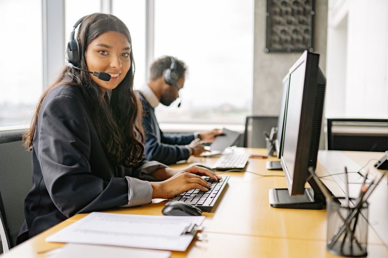 Customer service representative wearing a headset at a contact centre desk