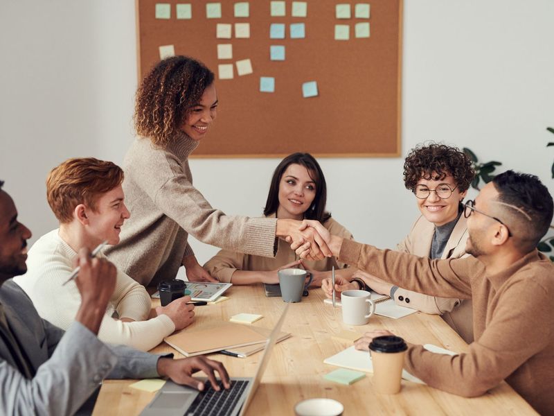 Recruiters and a client hiring team shaking hands across a meeting table