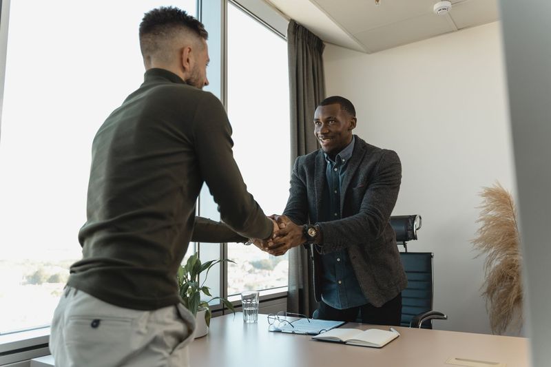 Hiring manager shaking hands with a newly placed candidate in a bright office